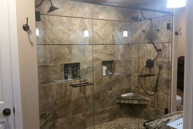 Стильный дизайн: ванная комната среднего размера в стиле неоклассика (современная классика) с душевой кабиной, душем в нише, унитазом-моноблоком, коричневой плиткой, керамической плиткой, бежевыми стенами, полом из галечной плитки, врезной раковиной, коричневым полом и душем с распашными дверями - последний тренд