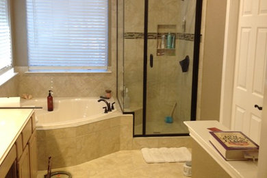Пример оригинального дизайна: большая главная ванная комната в классическом стиле с фасадами с выступающей филенкой, светлыми деревянными фасадами, угловой ванной, угловым душем, бежевой плиткой, керамической плиткой, коричневыми стенами, полом из керамогранита, столешницей из искусственного кварца, коричневым полом, душем с распашными дверями и белой столешницей
