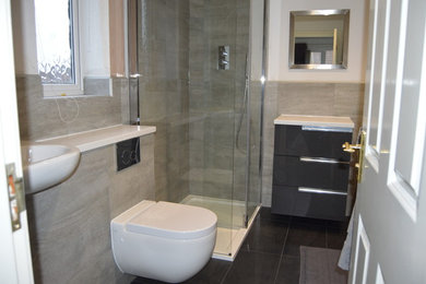 Photo of a modern wet room bathroom in Other with flat-panel cabinets, grey cabinets, a wall mounted toilet and solid surface worktops.