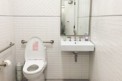 Aménagement d'une salle de bain moderne avec WC à poser, un carrelage blanc, un mur blanc, un sol en carrelage de porcelaine et un lavabo suspendu.