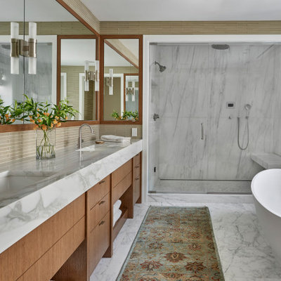 Example of a mid-sized transitional master beige tile and glass sheet marble floor, white floor and double-sink bathroom design in Chicago with flat-panel cabinets, medium tone wood cabinets, beige walls, an undermount sink, marble countertops, a hinged shower door, white countertops and a built-in vanity