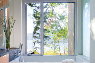 Пример оригинального дизайна: ванная комната в стиле модернизм с плоскими фасадами, фасадами цвета дерева среднего тона и отдельно стоящей ванной