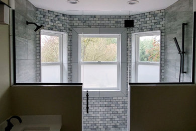 This is an example of a large classic ensuite bathroom in Portland with recessed-panel cabinets, grey cabinets, a freestanding bath, a double shower, a two-piece toilet, grey tiles, marble tiles, beige walls, dark hardwood flooring, a submerged sink, engineered stone worktops, brown floors, a hinged door and white worktops.