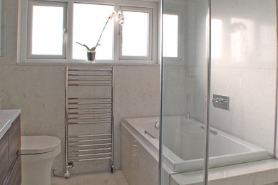 Medium sized contemporary family bathroom in London with flat-panel cabinets, dark wood cabinets, a built-in bath, a walk-in shower, a one-piece toilet, white tiles, stone slabs, white walls, marble flooring, an integrated sink, engineered stone worktops, white floors, a hinged door and white worktops.