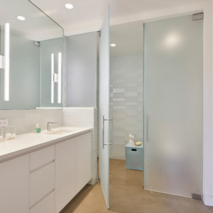 Idee per una grande stanza da bagno per bambini contemporanea con ante lisce, ante bianche, doccia a filo pavimento, piastrelle bianche, piastrelle di vetro, pareti bianche, pavimento in cemento, lavabo sottopiano, top in quarzo composito, WC a due pezzi e porta doccia a battente