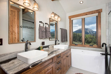 Mountain style master dark wood floor and brown floor bathroom photo in Denver with beaded inset cabinets, light wood cabinets, beige walls, a vessel sink and granite countertops
