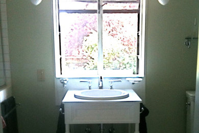 Aménagement d'une salle d'eau classique avec un placard avec porte à panneau encastré, des portes de placard blanches, WC séparés, un sol en carrelage de porcelaine et un lavabo posé.