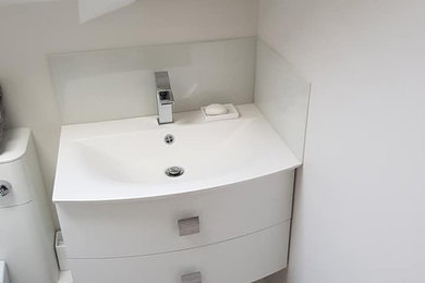 Réalisation d'une salle de bain principale minimaliste avec une douche d'angle, WC à poser, un mur beige, un lavabo suspendu et une cabine de douche à porte coulissante.