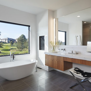 Imagen de cuarto de baño principal, moderno, con armarios con paneles lisos, puertas de armario de madera oscura, bañera exenta, paredes blancas, lavabo bajoencimera y suelo gris