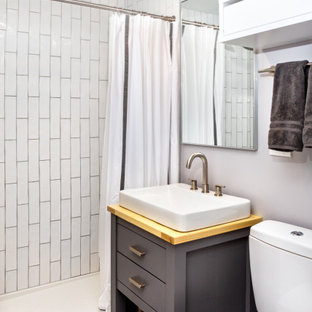 Mountain style 3/4 white tile and subway tile porcelain tile, gray floor and single-sink bathroom photo in Burlington with furniture-like cabinets, gray cabinets, a one-piece toilet, gray walls, a vessel sink, wood countertops and a freestanding vanity