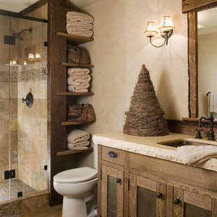 Example of a mountain style beige tile and travertine tile pebble tile floor alcove shower design in Sacramento with an undermount sink, shaker cabinets, medium tone wood cabinets, a two-piece toilet, beige walls and white countertops