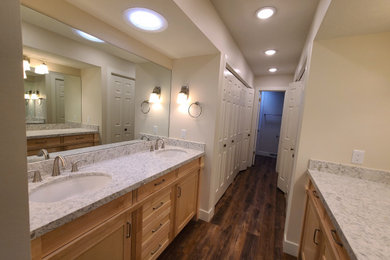 Diseño de cuarto de baño principal, doble y a medida clásico de tamaño medio con armarios estilo shaker, puertas de armario de madera clara, suelo vinílico y encimera de granito