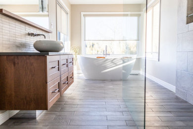 Example of a large transitional master gray tile and porcelain tile wood-look tile floor, gray floor and single-sink bathroom design in Ottawa with recessed-panel cabinets, medium tone wood cabinets, a two-piece toilet, beige walls, a vessel sink, quartz countertops, gray countertops, a niche and a freestanding vanity