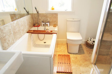 Photo of a small modern family bathroom in Devon with a built-in bath, a built-in shower, a two-piece toilet, beige tiles, white walls, marble flooring and a trough sink.