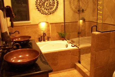 ロサンゼルスにある地中海スタイルのおしゃれな浴室 (家具調キャビネット、濃色木目調キャビネット、大型浴槽、一体型トイレ	、トラバーチンの床、ベッセル式洗面器、御影石の洗面台) の写真