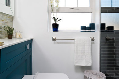 ダブリンにある小さなコンテンポラリースタイルのおしゃれなバスルーム (浴槽なし) (落し込みパネル扉のキャビネット、青いキャビネット、オープン型シャワー、一体型トイレ	、黒いタイル、サブウェイタイル、白い壁、セメントタイルの床、オーバーカウンターシンク、珪岩の洗面台、マルチカラーの床、オープンシャワー、白い洗面カウンター) の写真