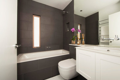 Design ideas for a medium sized contemporary bathroom in Sydney with a submerged sink, recessed-panel cabinets, white cabinets, a submerged bath, a shower/bath combination, a wall mounted toilet, black tiles, white walls, porcelain flooring, ceramic tiles and an open shower.