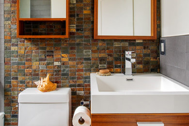 This is an example of a small contemporary family bathroom in Toronto with an integrated sink, flat-panel cabinets, medium wood cabinets, solid surface worktops, a one-piece toilet and slate tiles.