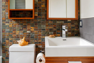 Inspiration for a small contemporary kids' slate tile bathroom remodel in Toronto with an integrated sink, flat-panel cabinets, medium tone wood cabinets, solid surface countertops and a one-piece toilet