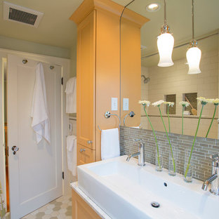 Modelo de cuarto de baño tradicional, pequeño, con lavabo de seno grande, combinación de ducha y bañera, armarios con paneles empotrados, baldosas y/o azulejos verdes, baldosas y/o azulejos de vidrio, encimera de mármol, paredes verdes, suelo de baldosas de cerámica y puertas de armario amarillas