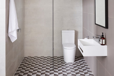 Foto på ett litet funkis badrum, med ett väggmonterat handfat, en öppen dusch och en toalettstol med hel cisternkåpa
