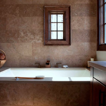 Soaking tub with travertine tiled wall