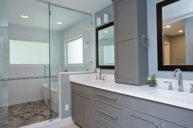 Exemple d'une grande salle de bain principale chic avec un placard à porte shaker, des portes de placard grises, une baignoire indépendante, un espace douche bain, WC séparés, un carrelage blanc, des carreaux de céramique, un mur bleu, un sol en carrelage de porcelaine, un lavabo encastré, un plan de toilette en quartz modifié, un sol gris, une cabine de douche à porte battante et un plan de toilette blanc.
