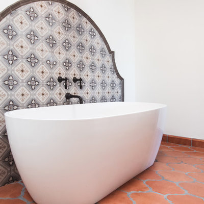 Huge southwest master multicolored tile and ceramic tile terra-cotta tile and orange floor bathroom photo in San Diego with raised-panel cabinets, medium tone wood cabinets, white walls, a vessel sink, a hinged shower door and gray countertops