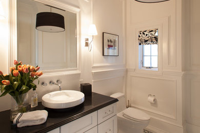 ニューヨークにあるトラディショナルスタイルのおしゃれな浴室 (シェーカースタイル扉のキャビネット、白いキャビネット、一体型トイレ	、白い壁、磁器タイルの床、ベッセル式洗面器、白い床、黒い洗面カウンター) の写真