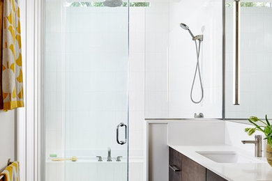 Photo of a contemporary bathroom in Austin with flat-panel cabinets, dark wood cabinets, grey tiles, porcelain tiles, engineered stone worktops, an alcove shower, white walls, a submerged sink and a hinged door.