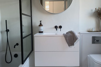 Small contemporary shower room bathroom in London with flat-panel cabinets, white cabinets, a built-in bath, a wall mounted toilet, grey tiles, grey walls, marble flooring, a wall-mounted sink, solid surface worktops, white floors, a hinged door and white worktops.