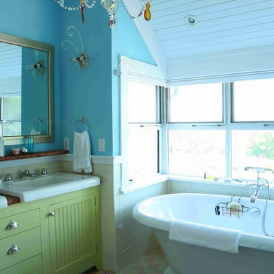 Mid-sized eclectic master mosaic tile floor freestanding bathtub photo in New York with beaded inset cabinets, green cabinets, a one-piece toilet, blue walls, an integrated sink and solid surface countertops