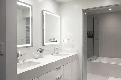 Example of a mid-sized minimalist master beige tile and porcelain tile dark wood floor bathroom design in Los Angeles with flat-panel cabinets, white cabinets, a one-piece toilet, white walls, an undermount sink and quartz countertops