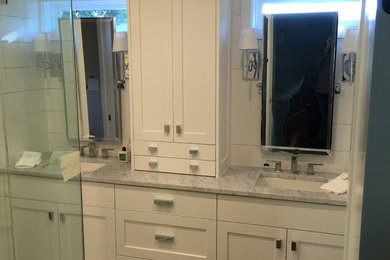 Cette photo montre une petite salle de bain principale chic avec un placard à porte plane, des portes de placard blanches, un mur blanc, un sol en bois brun, un lavabo encastré et un plan de toilette en marbre.