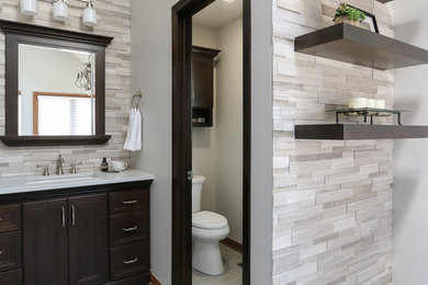 Inspiration for a large transitional master gray tile and porcelain tile porcelain tile bathroom remodel in Chicago with recessed-panel cabinets, dark wood cabinets, a two-piece toilet, gray walls, an undermount sink and quartz countertops