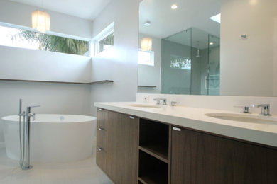 Freestanding bathtub - mid-sized contemporary master porcelain tile and white floor freestanding bathtub idea in Los Angeles with flat-panel cabinets, dark wood cabinets, white walls, an undermount sink and solid surface countertops