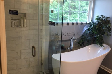 Inspiration for a mid-sized modern master white tile and ceramic tile ceramic tile and black floor bathroom remodel in Charlotte with recessed-panel cabinets, beige cabinets, a two-piece toilet, a drop-in sink, solid surface countertops, a hinged shower door, beige countertops and gray walls