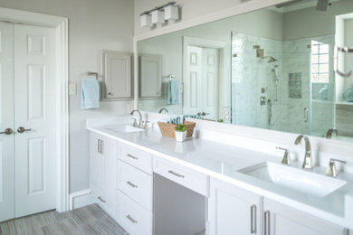 Example of a mid-sized transitional master gray tile and porcelain tile porcelain tile, gray floor and double-sink bathroom design in Dallas with recessed-panel cabinets, gray cabinets, a two-piece toilet, gray walls, an undermount sink, quartz countertops, a hinged shower door, white countertops and a built-in vanity