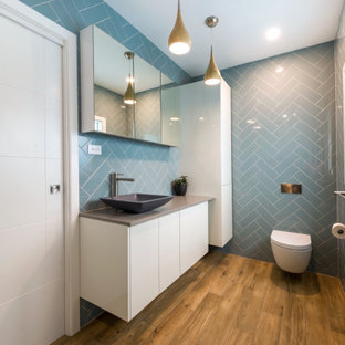 Foto di una piccola stanza da bagno con doccia moderna con ante gialle, WC sospeso, piastrelle blu, piastrelle in ceramica, pareti blu, pavimento in vinile, lavabo a bacinella, top in granito, pavimento multicolore, top grigio, un lavabo, mobile bagno sospeso e boiserie