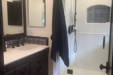 Example of a mid-sized mountain style master white tile and subway tile terra-cotta tile and red floor drop-in bathtub design in Los Angeles with furniture-like cabinets, brown cabinets, a one-piece toilet, white walls, a drop-in sink, quartz countertops and a hinged shower door