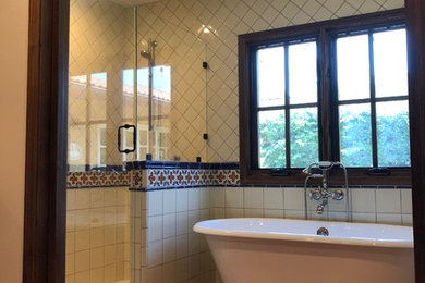 Inspiration for a mid-sized mediterranean master terra-cotta tile and red floor bathroom remodel in San Diego with raised-panel cabinets, dark wood cabinets, beige walls, an undermount sink, solid surface countertops, a hinged shower door and beige countertops