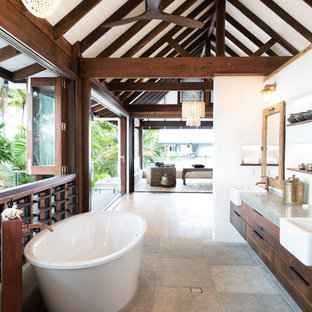 Tropical master bathroom in Cairns with flat-panel cabinets, medium wood cabinets, a freestanding tub, white walls, a drop-in sink, concrete benchtops, grey floor and grey benchtops.