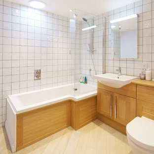 Design ideas for a mediterranean ensuite bathroom in Channel Islands with shaker cabinets, light wood cabinets, a corner bath, a shower/bath combination, a one-piece toilet, white tiles, a vessel sink, wooden worktops, beige floors and beige worktops.