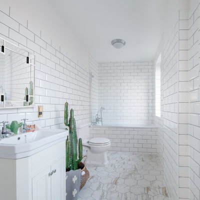 Large trendy 3/4 white tile and subway tile beige floor bathroom photo in London with recessed-panel cabinets, white cabinets, a one-piece toilet, white walls and a console sink