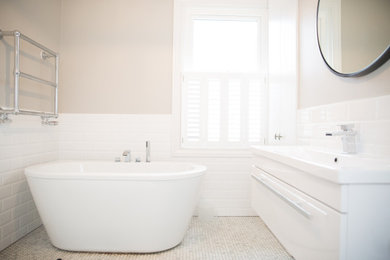 Small urban family bathroom in London with raised-panel cabinets, white cabinets, a freestanding bath, white tiles, ceramic tiles, pink walls, ceramic flooring, an integrated sink and white floors.