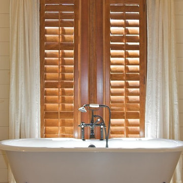 Stained plantation shutters next to claw foot tub