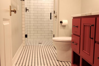 オマハにある小さなトランジショナルスタイルのおしゃれなバスルーム (浴槽なし) (赤いキャビネット、アルコーブ型シャワー、モノトーンのタイル、サブウェイタイル、グレーの壁、セラミックタイルの床、オーバーカウンターシンク、クオーツストーンの洗面台) の写真