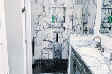 Example of a large transitional 3/4 gray tile and marble tile porcelain tile and black floor alcove shower design in San Francisco with recessed-panel cabinets, distressed cabinets, white walls, an undermount sink, marble countertops, a hinged shower door and gray countertops