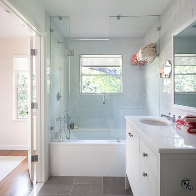 Inspiration for a timeless gray tile and stone tile tub/shower combo remodel in Austin with an undermount sink, white cabinets, an undermount tub and flat-panel cabinets