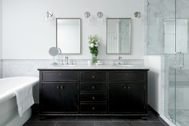 Photo of a large traditional ensuite bathroom in Vancouver with freestanding cabinets, dark wood cabinets, a freestanding bath, a double shower, a two-piece toilet, white tiles, marble tiles, grey walls, porcelain flooring, a submerged sink, marble worktops, black floors, a hinged door and white worktops.